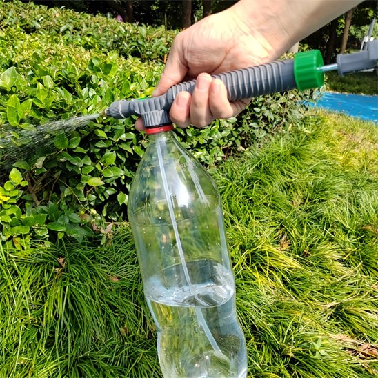 Pulverisateur gris avec bouteille de plastique tenu par main arrosant une  haie 