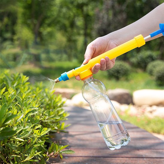 Pulverisateur jaune avec petite bouteille de plastique tenu par main arrosant plantes 