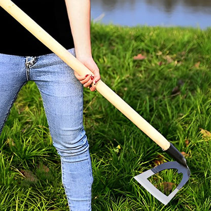 femme debout tenant Binette de jardinage creuse avec manche en bois, utilisée dans un champ de grandes herbes vertes avec lac