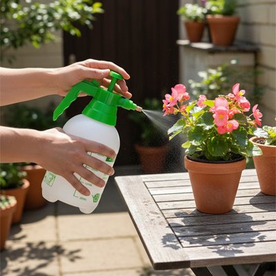 main tenant pulverisateur blanc  etvert arrosant fleur en pot